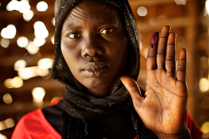 Sudan voters: Hellena Akwat holds up her ink-stained finger to show she voted