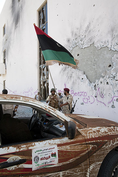 Sirte by Peter Beaumont: Two Libyan NTC fighters celebrate outside Sirte's massive convention centre