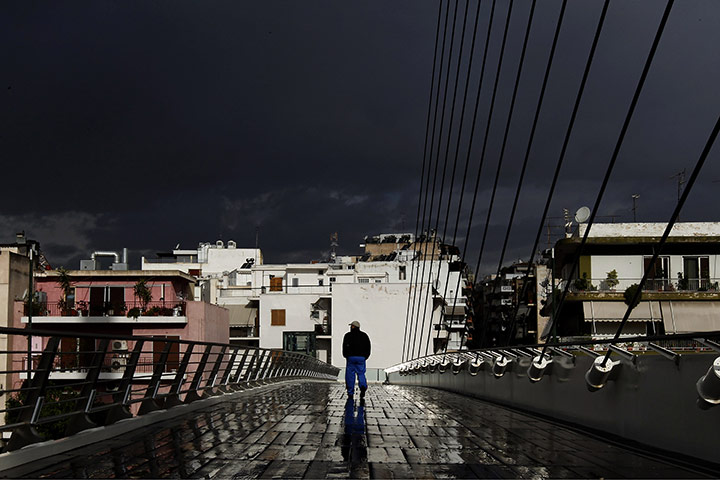 24 hours in pictures: Athens, Greece: A man walks on a bridge in the rain