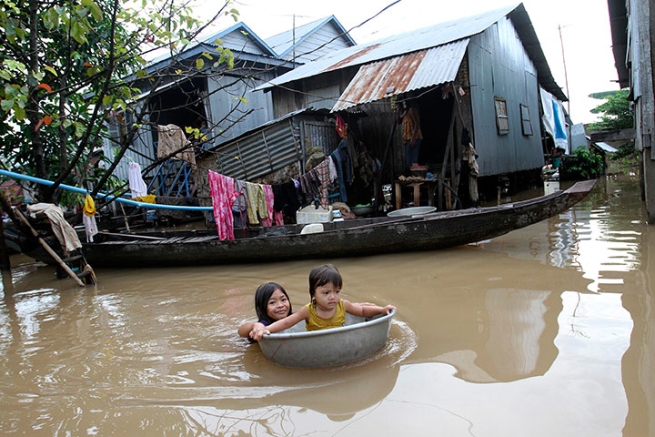 24 hours: Kandal province, Cambodia: A girl sits in a bucket as her sister pushes it