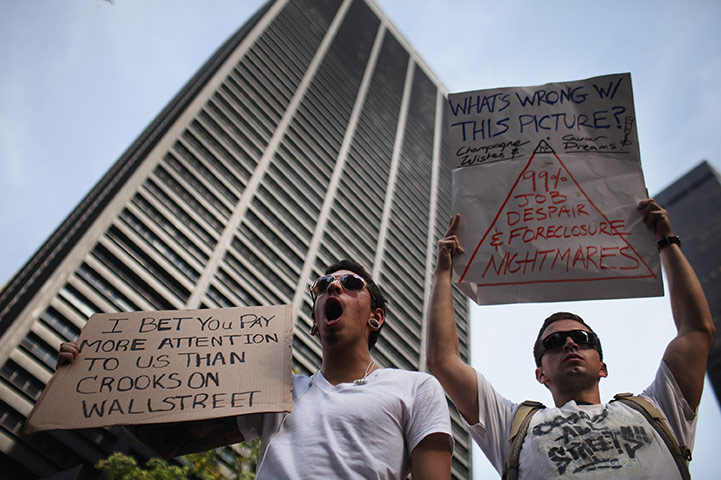 Occupy protests: New York:  Wall Street protesters hold up signs at Zuccotti Park