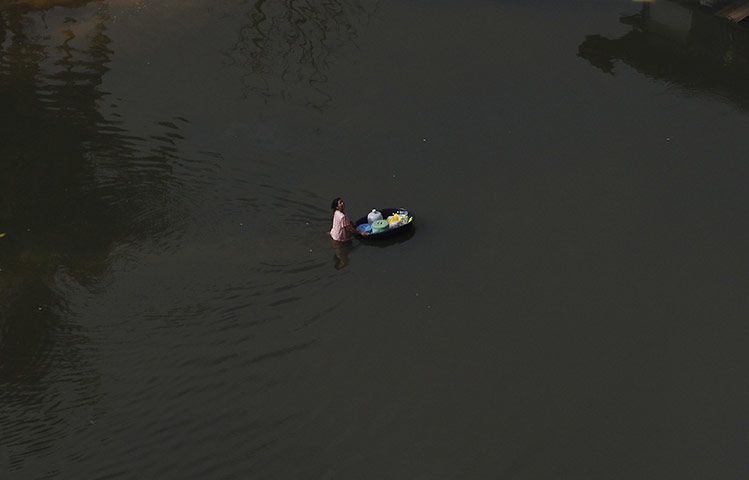 Thailand floods: A resident pushes a container through the flood in Nonthaburi