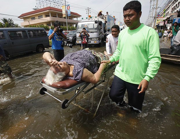 Thailand floods: A rescue worker evacuates a woman from a flooded area in Pathum Thani