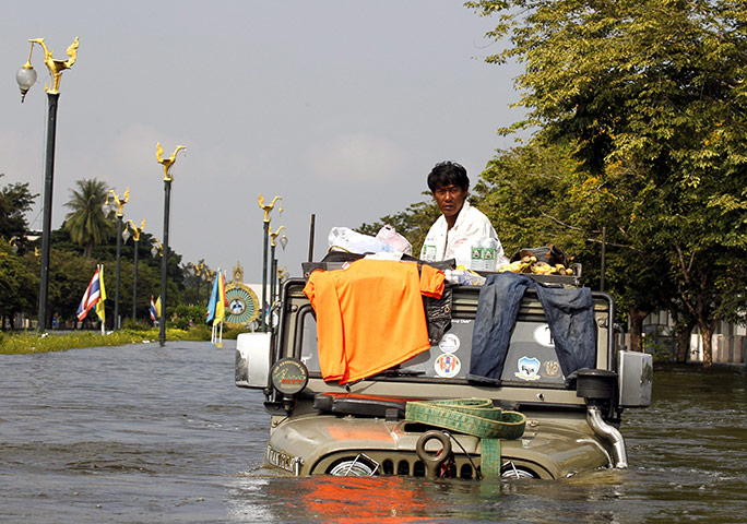 Thailand floods: A Thai resident sits on a flood-submerged jeep on a street in Ayutthaya