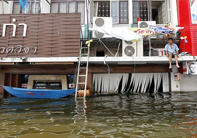 Thailand floods: A Thai resident waits for help on a flood submerged building
