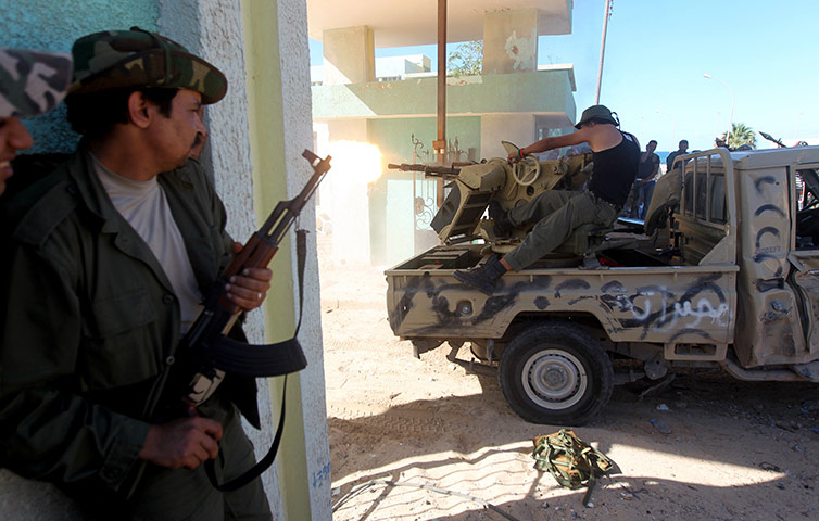 Sirte street battles: An NTC fighter watches comrades fire their gun 