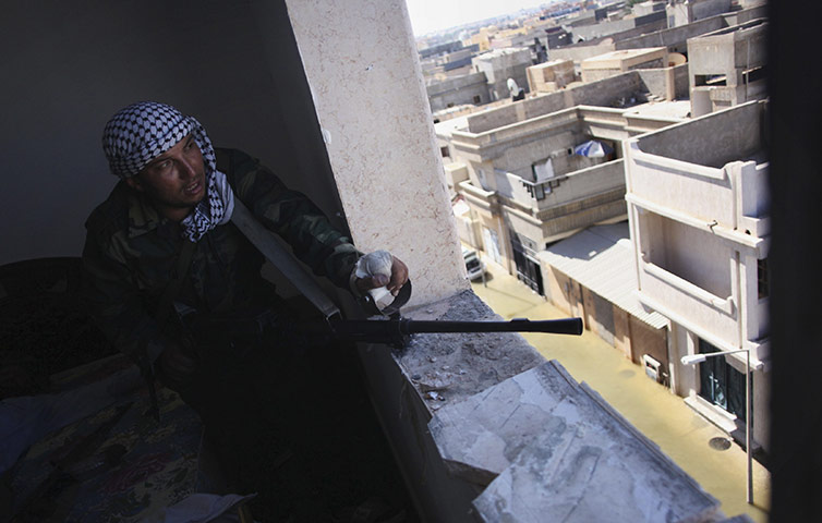 Sirte street battles: A revolutionary fighter fires his machine gun towards loyalist positions 