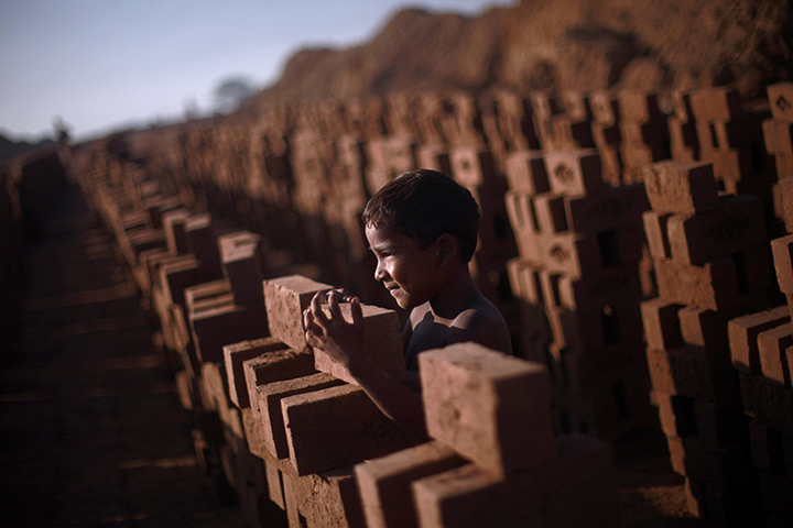 24 hours in pictures: Pakistani boy stands between bricks at a factory