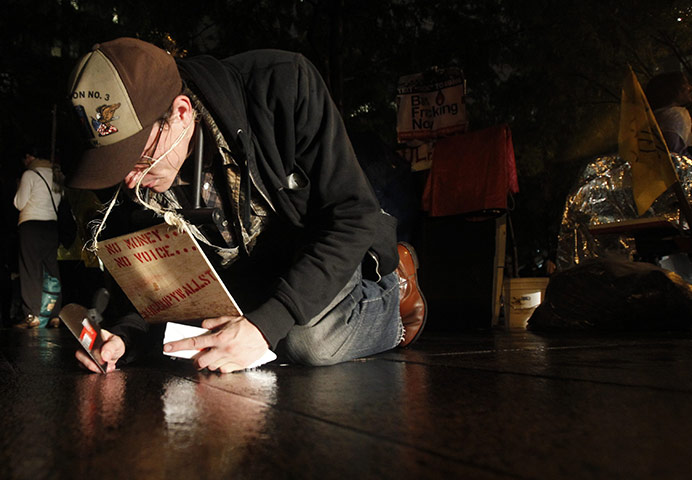 Occupy Wall Street: A protester scrapes paint that has dripped onto the concrete the park