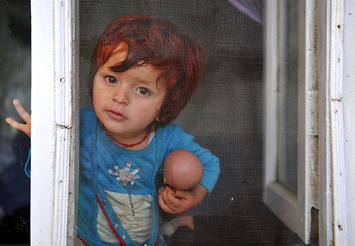 24 hours: Kabul, Afghanistan: An Afghan toddler looks out of a window inside a house