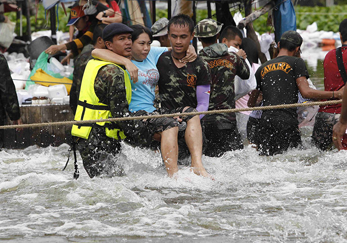 Thailand flooding: Soldiers carry a woman through a flooded street