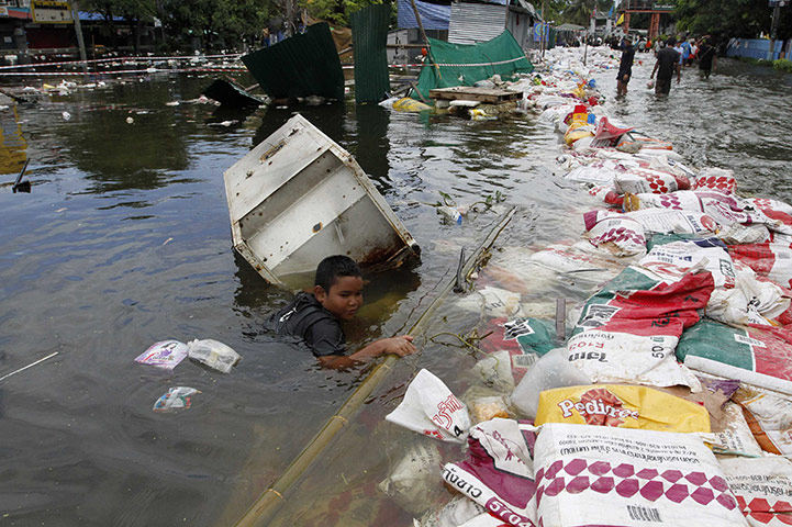 Thailand flooding: A boy pulls a refrigerator along a flooded street