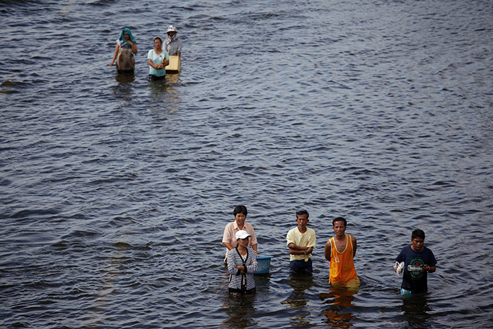 Thailand flooding: People wade through the water on a flooded highway in Ayutthaya province