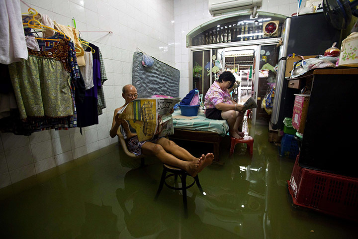 Thailand flooding: People read newspapers at their flooded home in Bangkok