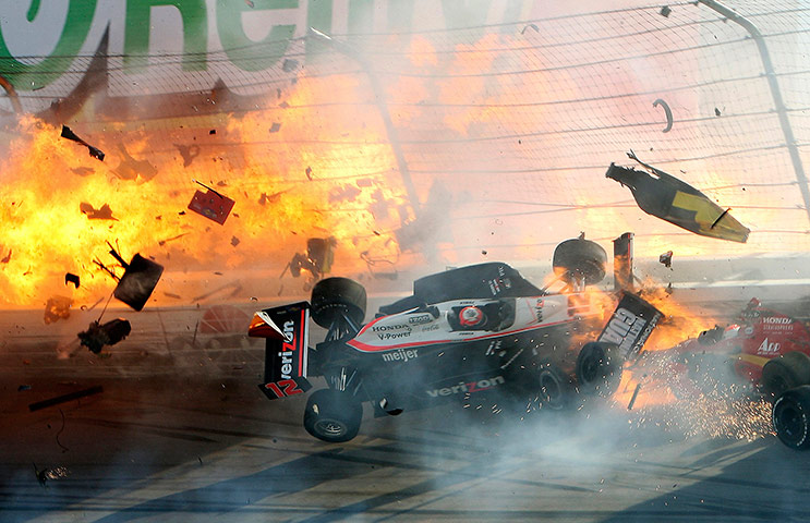 Dan Wheldon Retrospective: Race car of driver Power hits the wall as flames from Wheldon's car burst