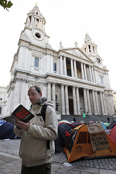 Occupy London: A man reads a book near protesters' tents outside St Paul's Cathedral