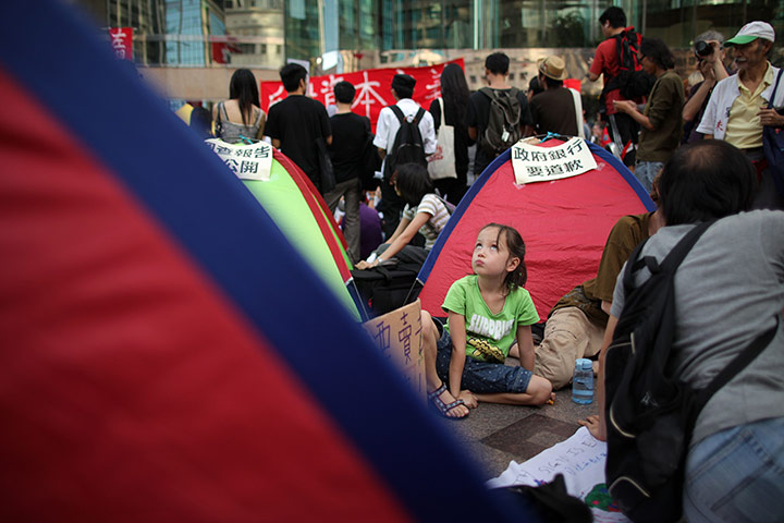 Occupy World Protests: A girl sits among tents outside the Hong Kong stock exchange 