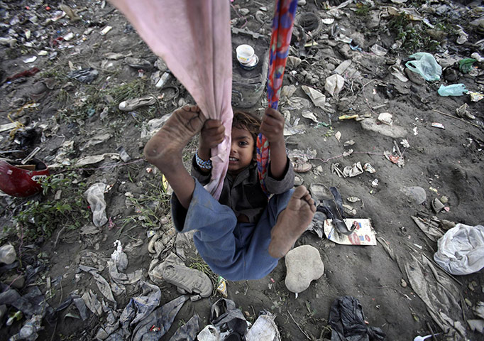 24 hours in pictures: Kathmandu, Nepal: A child living in a slum plays on a swing under a bridge