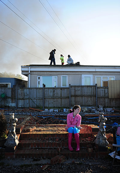 Dale Farm camp: A young girl sits on the ground on a travellers site on Dale Farm