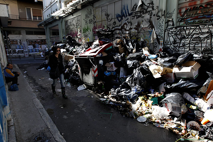 Greece strikes & protests: A woman passes a pile of rotting rubbish in a narrow street in Athens
