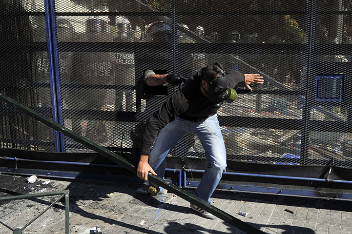 Greece strikes & protests: A riot policeman catches a protester who attacked a steel barricade 