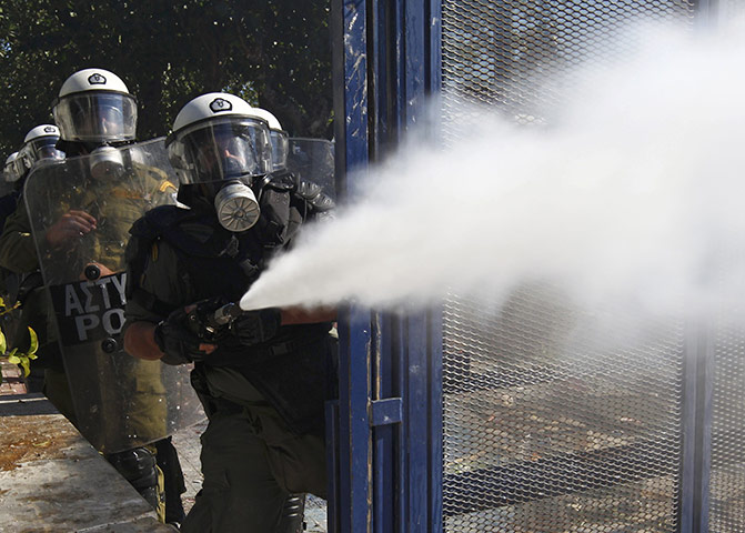 Greece strikes & protests: A riot policeman sprays tear gas at demonstrators 