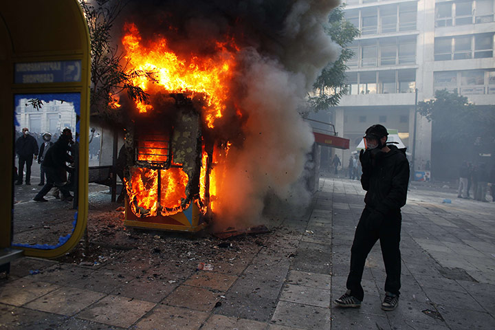 Greece strikes & protests: A protester wearing a gas mask stands next to a fire 