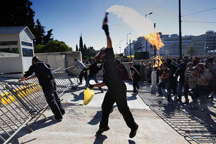 Greece strikes & protests: A masked youth throws a petrol bomb at police during riots 