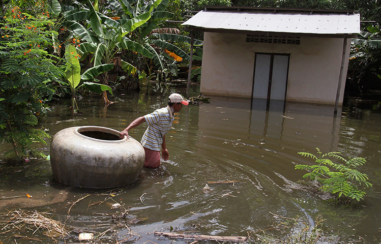 Cambodia floods: A man pulls a giant jar in flood waters on a street in Kandal province 