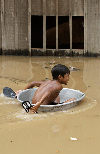 Cambodia floods: A boy uses an aluminum pot at flooded Croy Changvar village in Phnom Penh