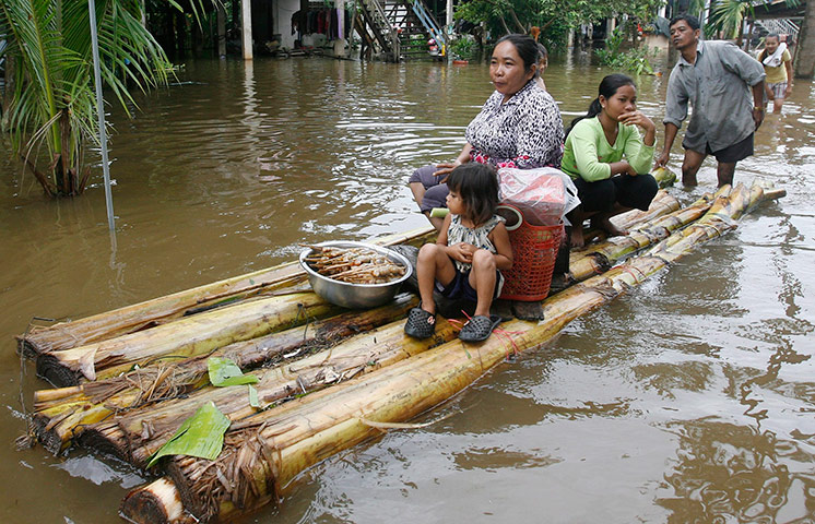 Cambodia floods: Cambodian villagers on a makeshift raft travel though a flooded street