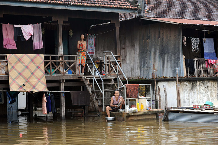 Cambodia floods: Cambodians wash pots in floodwaters at Kian Svay district 