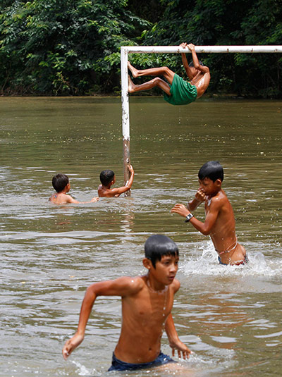 Cambodia floods: Children play in flood waters on a goal post in Kandal 