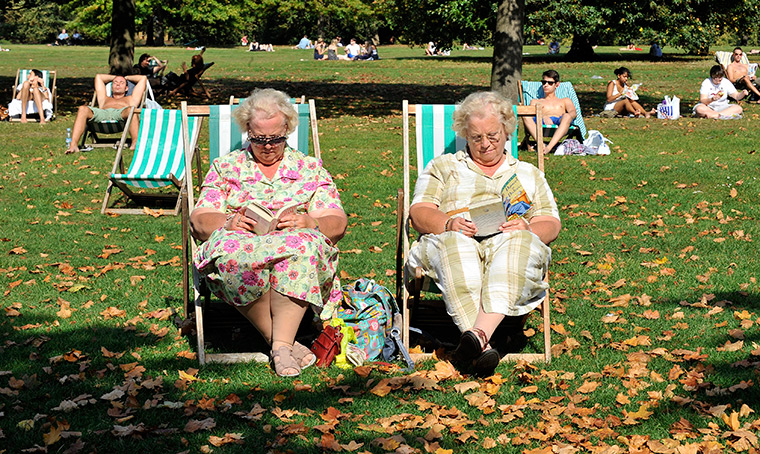 UK October heatwave: Elderly women enjoy a peaceful read on deckchairs in Hyde Park, London