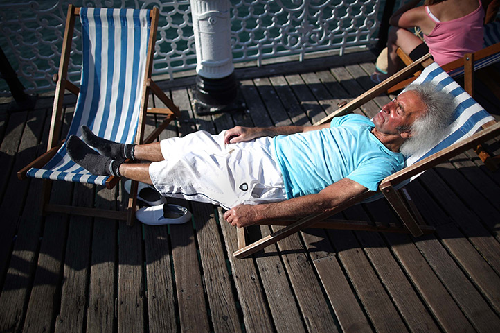UK October heatwave: A man sleeps on two deck chairs on the pier in Brighton