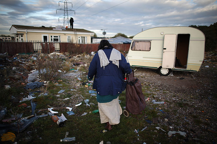 Dale Farm: a woman makes her way past an abandoned caravan