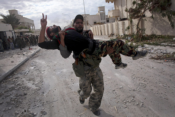 Sirte falls: An injured Libyan rebel fighter is carried by another fighter 