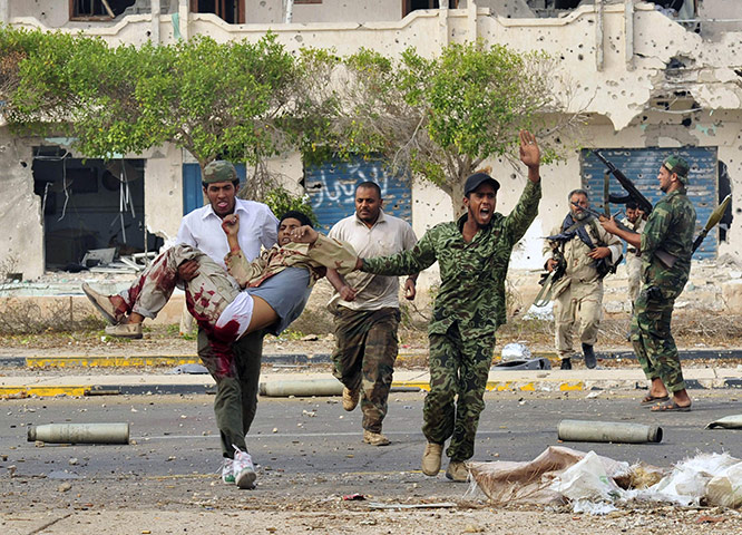 Sirte falls: Anti-Gaddafi fighters carry an injured comrade during clashes