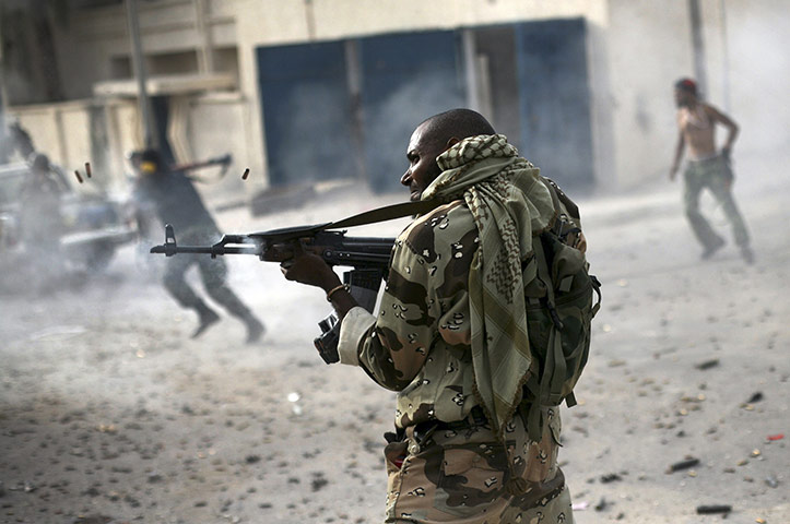 Sirte falls: A Libyan rebel fighter fires his machine gun toward loyalist positions