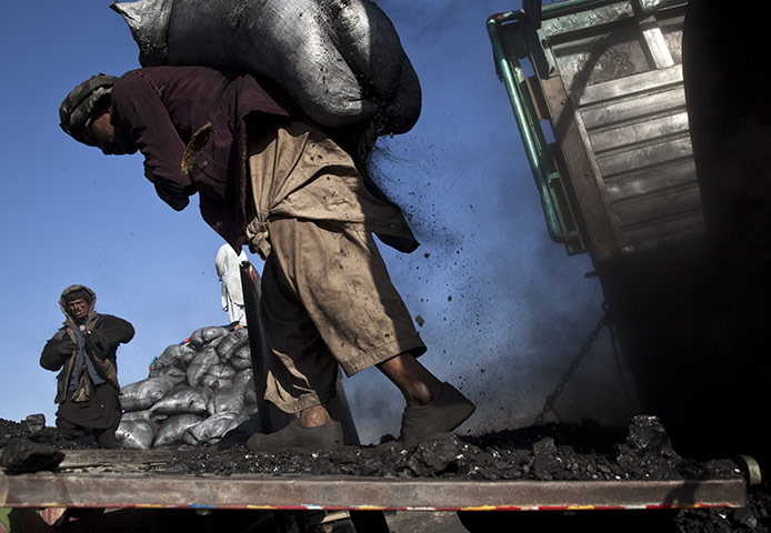 24 hours in pictures: A labourer carries a sack of coal to be loaded onto a truck, Kabul