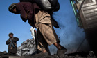 A labourer carries a sack of coal at a coal dump site, Kabul