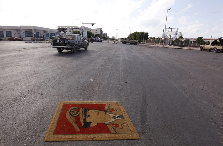 Cult of Gaddafi: A carpet with a picture of Muammar Gaddafi lies in a street in Sirte