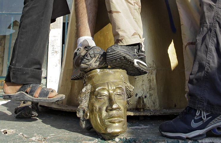 Cult of Gaddafi: Rebel fighters trample on a head of a statue of Gaddafi 