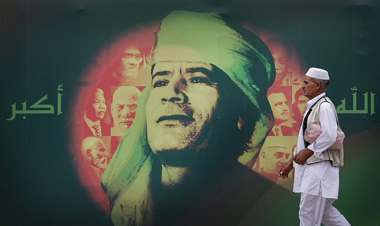 Cult of Gaddafi: A man walks past an anniversary banner showing  Gaddafi 