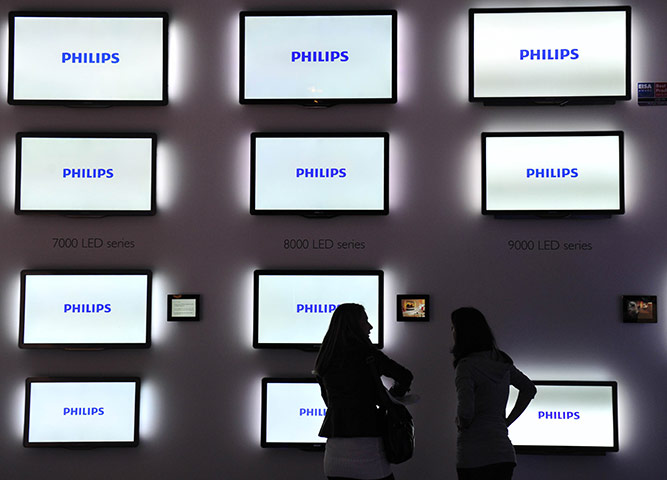 Week in Business: Visitors stand in front of LED TVs at the Philips stand at a trade fair