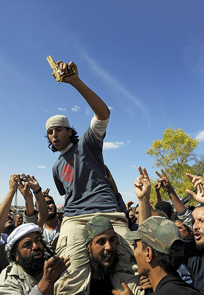 Libya celebrates: Young man holding the alleged gold-plated gun of Muammar Gaddafi