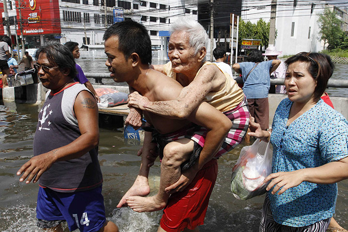 Thailand Floods: a man carries an elderly woman