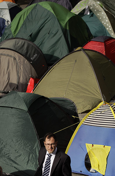 Occupy London: A commuter walks past tents put up by protesters 