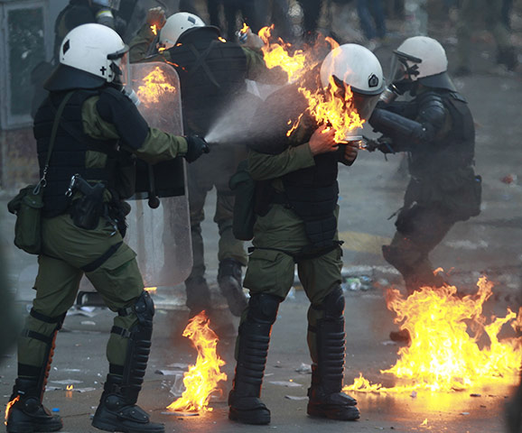 24 hours in pictures: Athens, Greece: A riot policeman tries to extinguish a fire