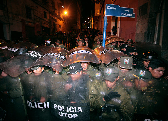24 hours in pictures: La Paz, Bolivia: Riot policemen shield themselves during a demonstration
